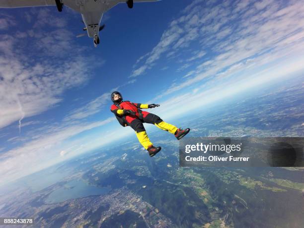 skydiver jumped off an aircraft and is tracking backwards in a straight position high in the blue sky. - base jumping stock pictures, royalty-free photos & images