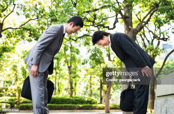 bowing - two japanese businessmen greeting each other in tokyo - thank you smile stock pictures, royalty-free photos & images