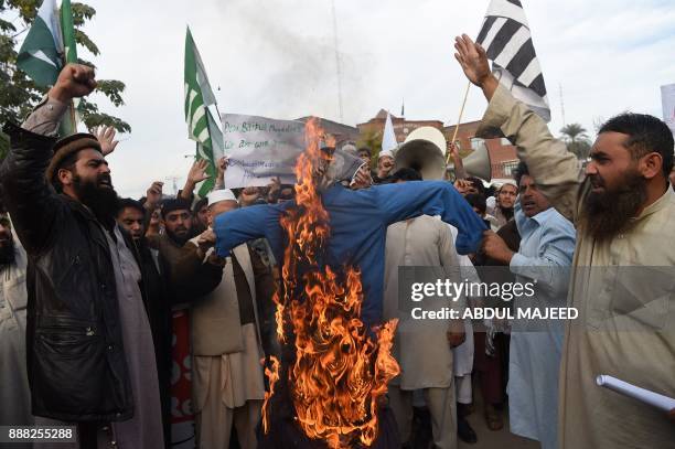 Protesters burn an effigy depecting US President Donald Trump during an anti-US and Israeli protest in Peshawar on December 8 following Trump's...