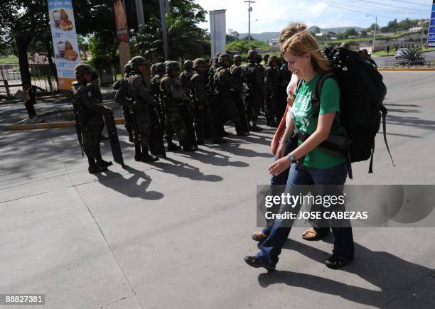 Tourists walk past soldiers falling in at Tegucigalpa's international airport Toncontin, after it was militarized and all flights suspended on July...