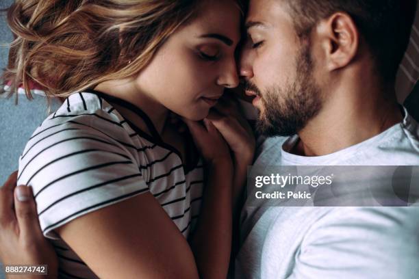 loving couple in consoling embrace - man and woman kissing in bed stock pictures, royalty-free photos & images