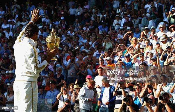 Roger Federer of Switzerland waves to the crowd as he celebrates with the trophy after the men's singles final match against Andy Roddick of USA on...