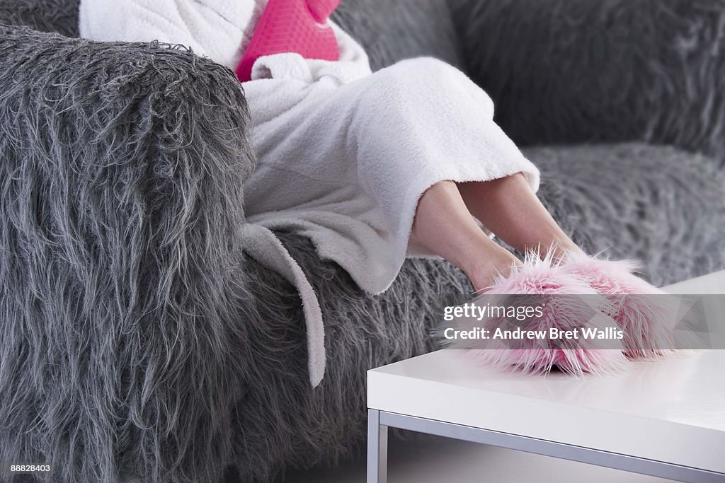 Woman in fuzzy slippers and bathrobe on sofa