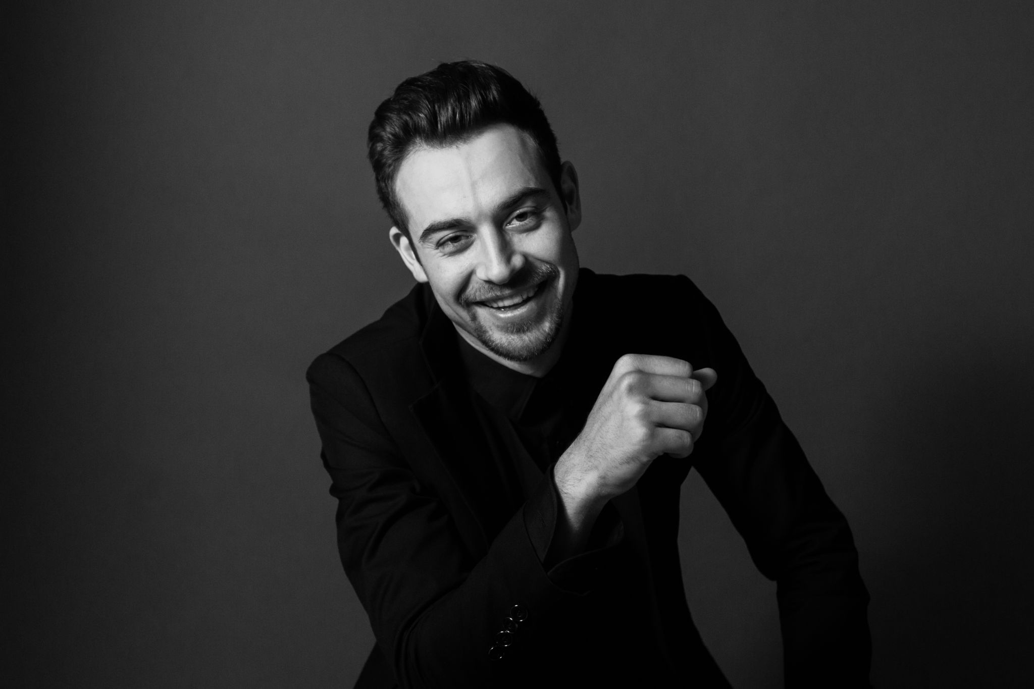 Black and white portrait of a young handsome man in a suit, smiling and looking at the camera Black and white portrait of a young handsome man in a suit, smiling and looking at the camera