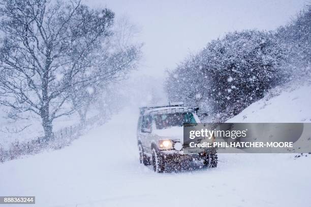 4x4 drives across a snow-covered road in the hills above Llangollen, north Wales, on December 8 as Storm Caroline plunges temperatures across the UK....