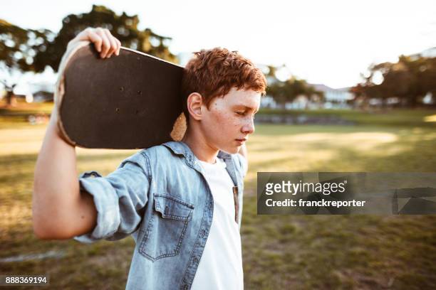trauriges kind mit dem skateboard auf der schulter - teenager boy stock-fotos und bilder