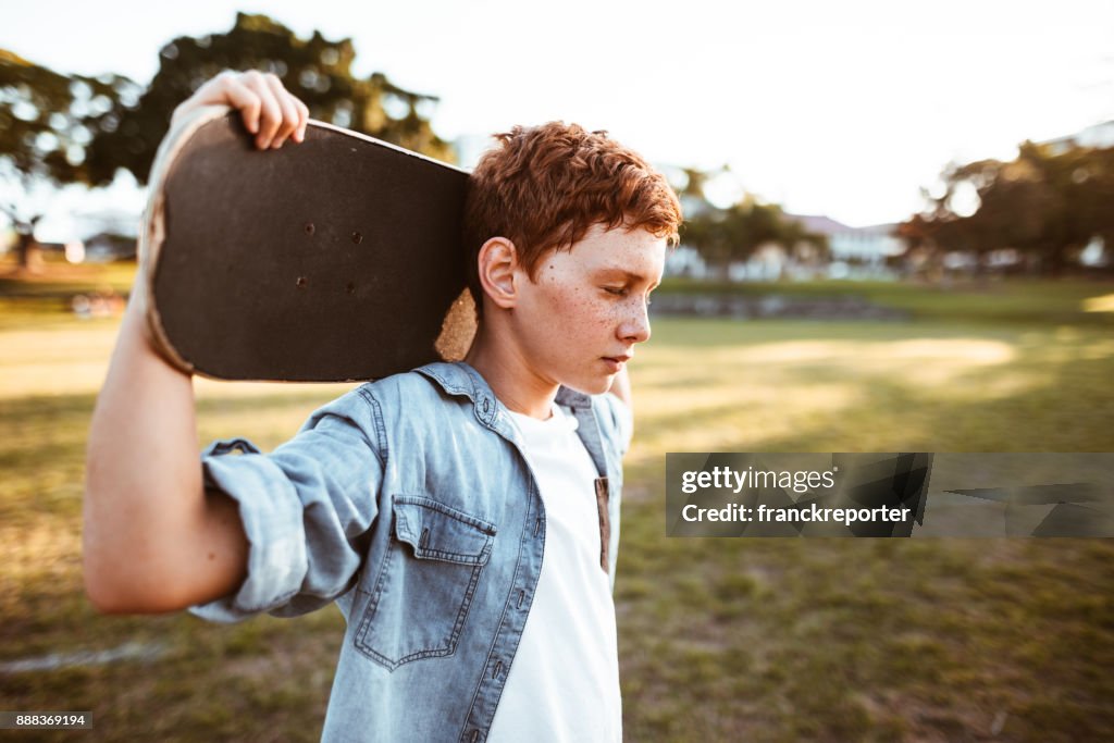 Sorgliga kid med skateboard på axeln