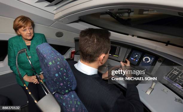 German Chancellor Angela Merkel listens to driver Martin Spiegelhauer as she attends a part of the opening passage of a special ICE railway route...