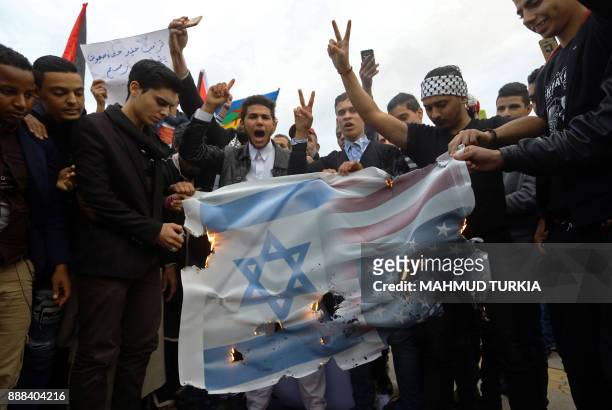 Libyan and Palestinian demonstrators burn a banner bearing an image of the American and Israeli flag during a protest denouncing US President Donald...