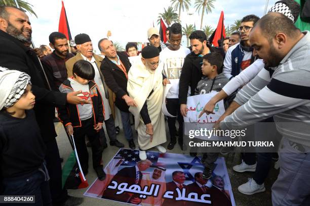 Demonstrators stand on a poster bearing an image of US President Donald Trump attending the Arab Islamic American Summit during a protest denouncing...