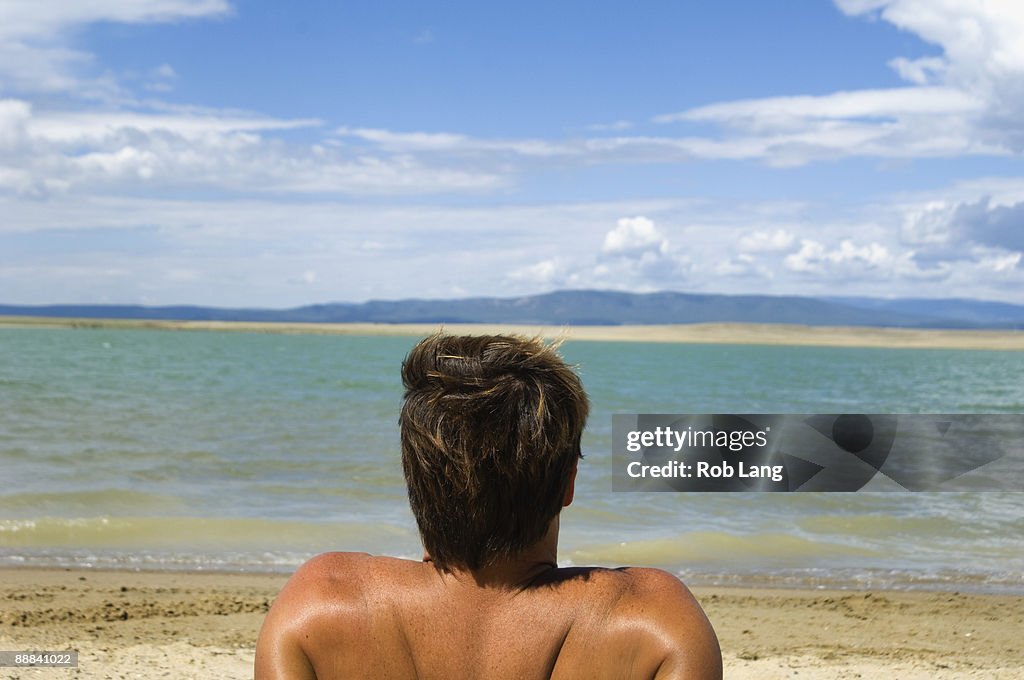 Back view of man sitting on beach