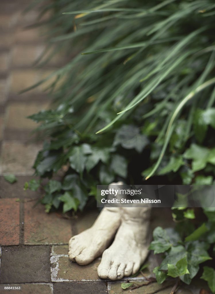 Feet sculpture on bricks by garden