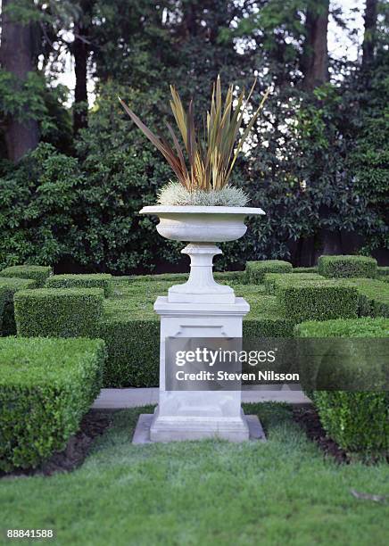 pedestal urn in garden with manicured hedges - urn flowers stock pictures, royalty-free photos & images