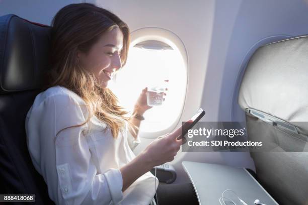 young woman enjoys in flight beverage and wifi - assento de veículo imagens e fotografias de stock