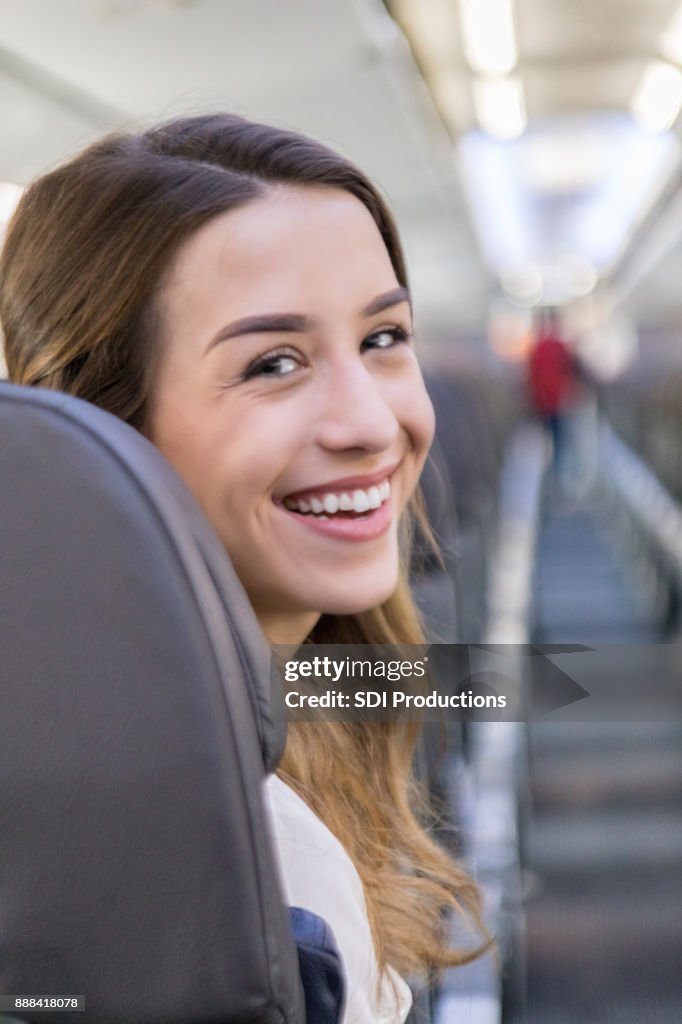 Young woman smiles for camera in aircraft isle seat