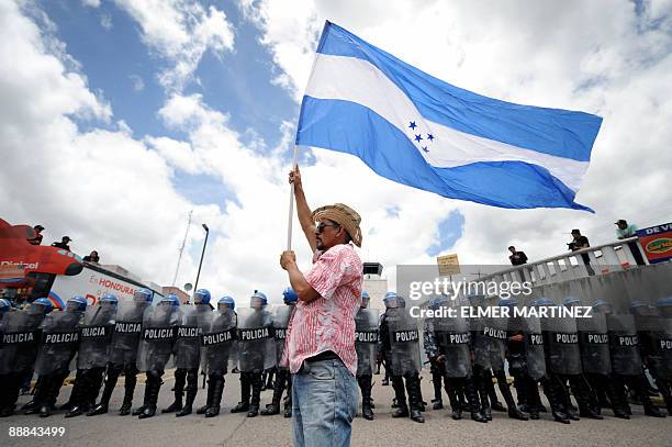 Supporter of Honduran President Manuel Zelaya holds a national flag in front of Honduran soldiers outside Toncontin international airport in...