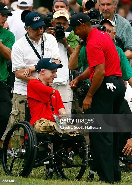 Tiger Woods greets PFC Brendan Marrocco of Staten Island, New York, who was wounded in Iraq, near the 18th green during the final round of the AT&T...