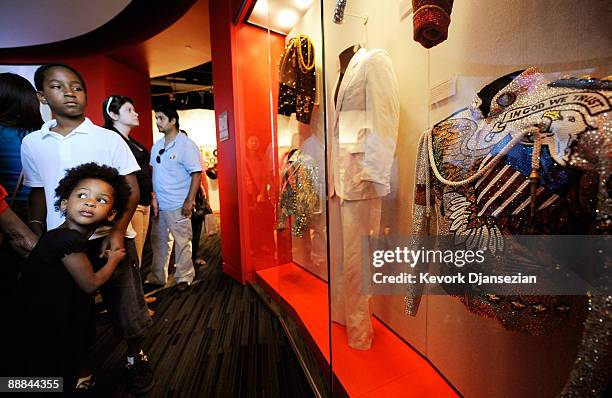 Fans of the late Micahel Jackson look at outfits previously worn by the pop star at a memorial exhibit held at the Grammy Museum on July 5, 2009 in...