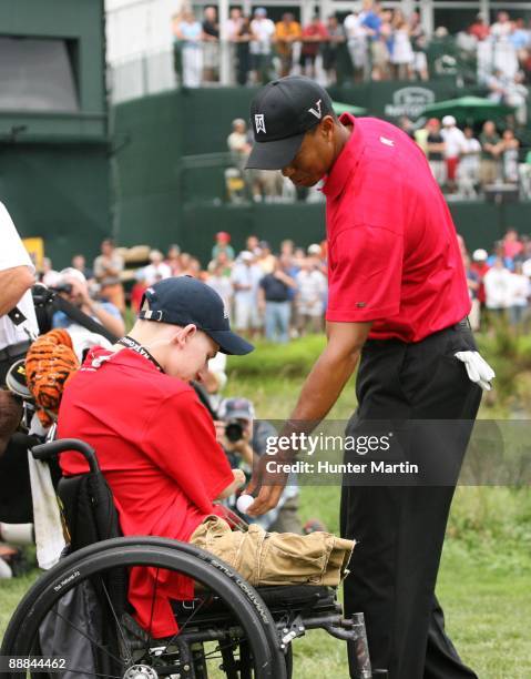 Tiger Woods greets PFC Brendan Marrocco of Staten Island, New York, who was wounded in Iraq, near the 18th green during the final round of the AT&T...