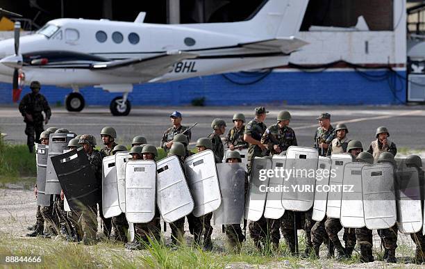 Honduran riot squad officers stand guard as they wait for the plane carrying ousted Honduran President Manuel Zelaya at Toncontin International...
