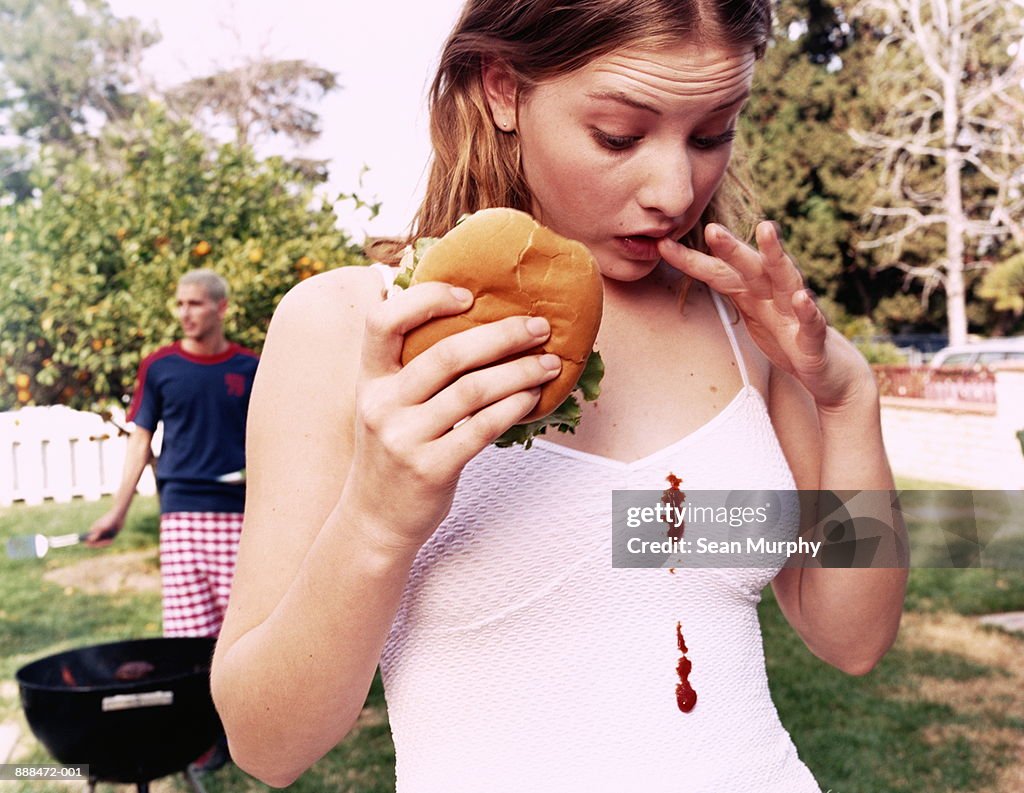 Teenage girl (16-18) looking at  ketchup stains on white dress