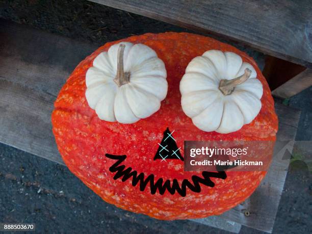 orange pumpkin with two small white pumkins as eyes and a black squiggly smiling mouth and triangle nose. - marie hickman stock pictures, royalty-free photos & images