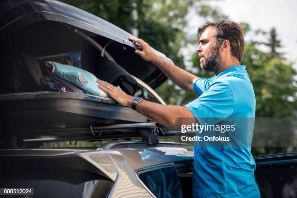 men filling cargo box container on roof rack for vacations - luggage rack stock pictures, royalty-free photos & images