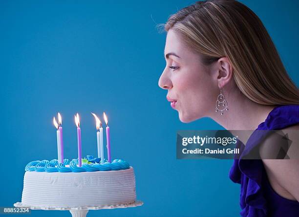 young woman blowing candles on birthday cake, studio shot - soprando - fotografias e filmes do acervo