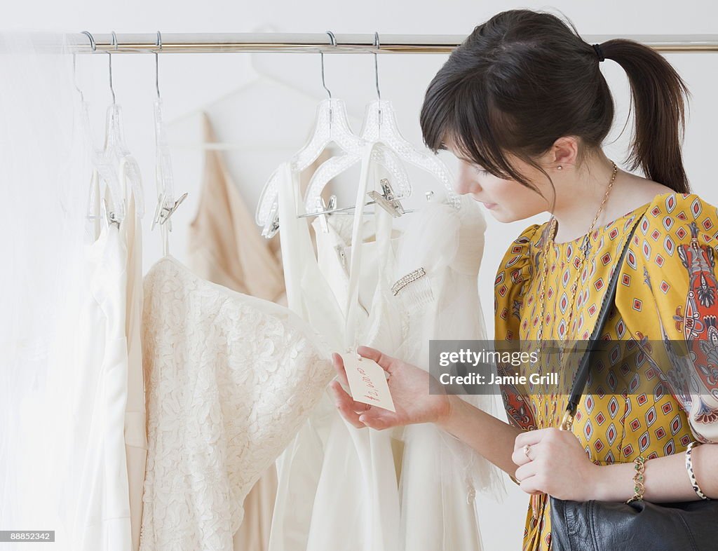 Young woman observing wedding dress in shop