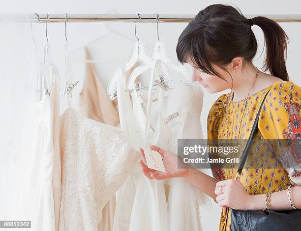 young woman observing wedding dress in shop - bridal shop stockfoto's en -beelden