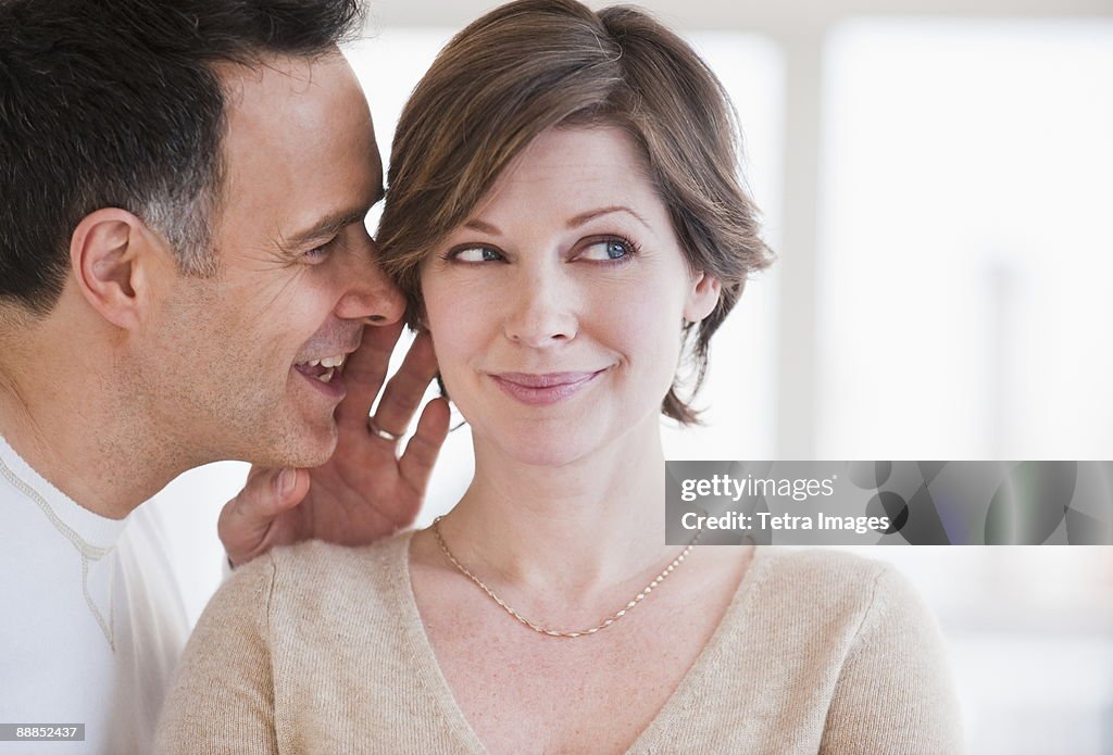 Man whispering to womans ear