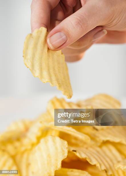 womans hand taking potato chip - gerippt stock-fotos und bilder