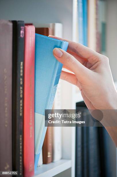 woman removing book from shelf, close-up - book close up stock-fotos und bilder