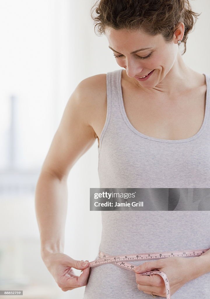 Mid adult woman measuring waist