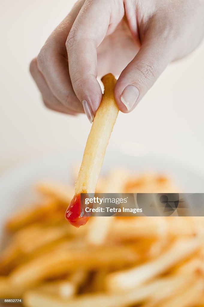 Woman with french fries, close-up of hand