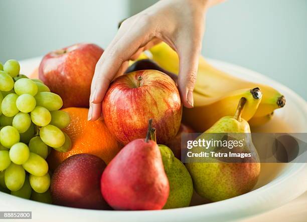 womans hand taking apple from fruit bowl - fruitschaal stockfoto's en -beelden