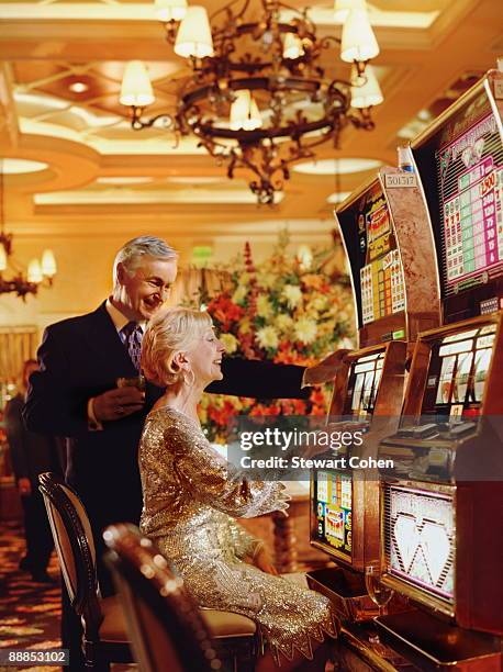 usa, nevada, las vegas, senior couple in casino playing on slot machines - las vegas casino stock pictures, royalty-free photos & images