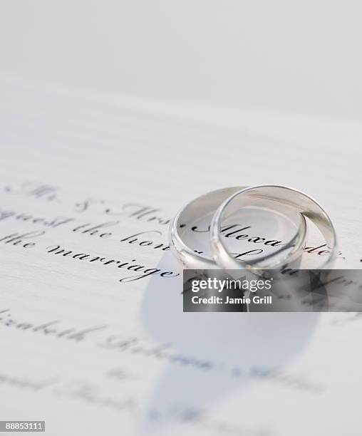 two wedding rings on marriage certificate, studio shot - marriage certificate stock pictures, royalty-free photos & images