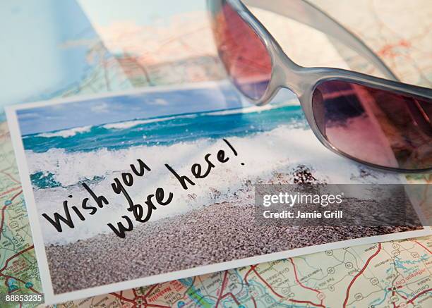 close-up of sunglasses and postcard on map - ansicht stockfoto's en -beelden