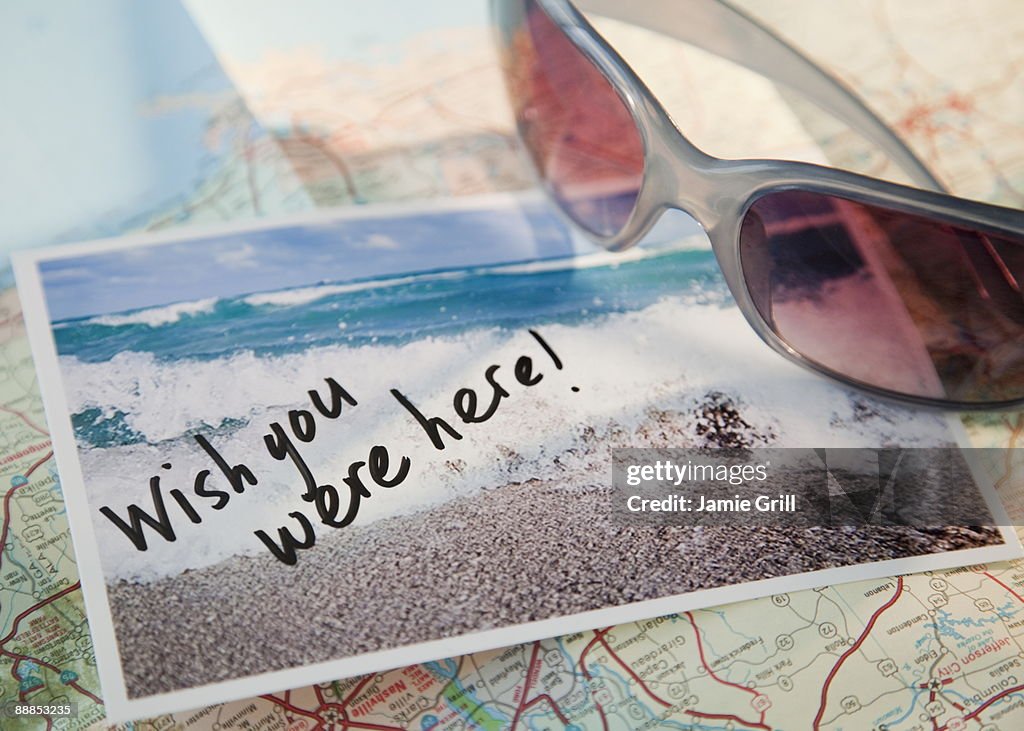 Close-up of sunglasses and postcard on map