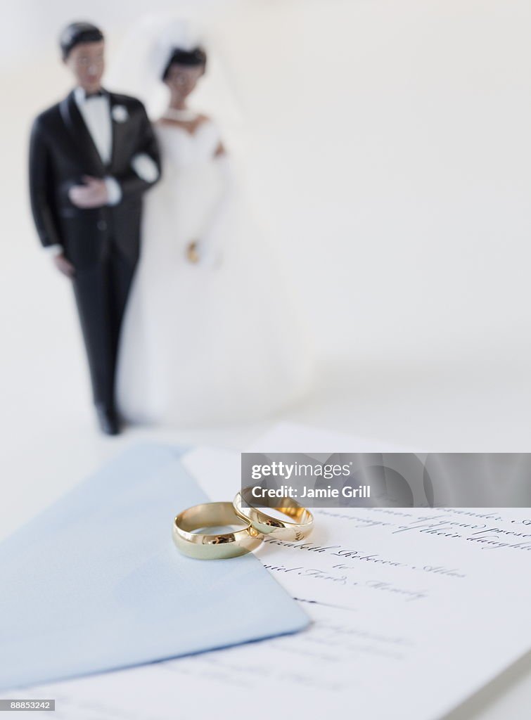 Wedding rings by bride and groom cake toppers on marriage certificate