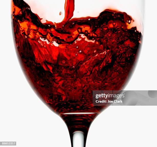 red wine being poured into wineglass, close-up - wine splash stock pictures, royalty-free photos & images