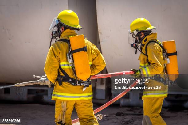team of firefighters on training - gas pump help stock pictures, royalty-free photos & images