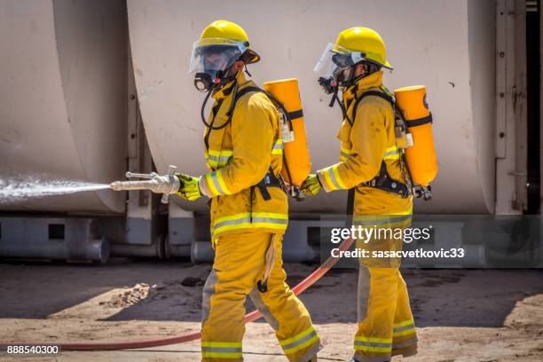 team of firefighters on training - gas pump help stock pictures, royalty-free photos & images