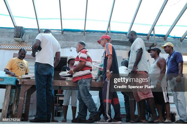 Men eat at a communal kitchen on the nearly destroyed island of Barbuda on December 8, 2017 in Cordington, Barbuda. Barbuda, which covers only 62...