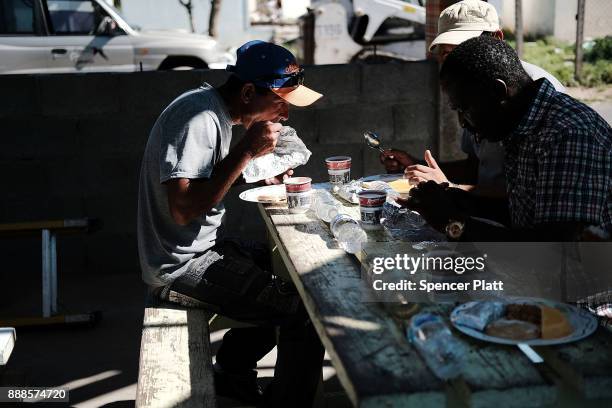 Men eat at a communal kitchen on the nearly destroyed island of Barbuda on December 8, 2017 in Cordington, Barbuda. Barbuda, which covers only 62...