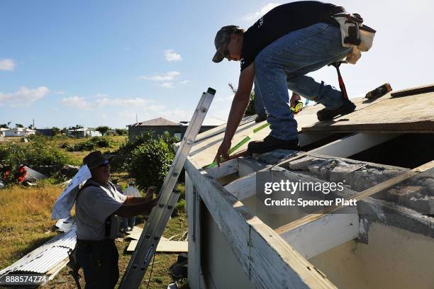 Workers from the charity Samaritan's Purse place a new roof on a home on the nearly destroyed island of Barbuda on December 8, 2017 in Cordington,...