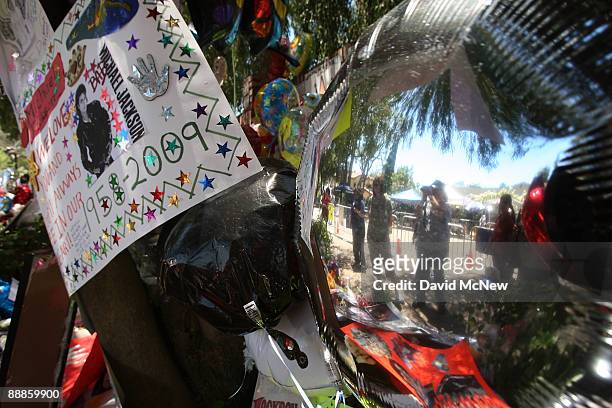 Fans are reflected in a metallic balloon as they pay their respects at a makeshift memorial outside the Jackson family home as Los Angeles prepares...