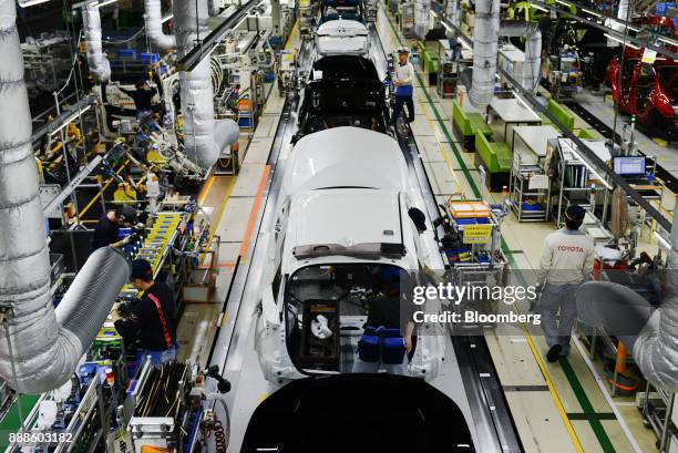 Workers assemble vehicles on the Prius hybrid and Priyus plug-in hybrid vehicle production line of the Toyota Motor Corp. Tsutsumi plant in Toyota...