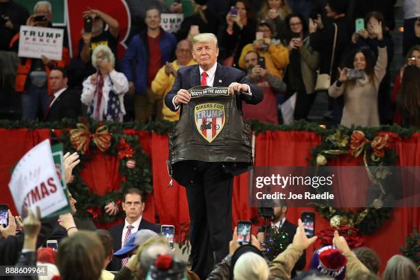 President Donald Trump holds up a vest given to him to autograph during a rally at the Pensacola Bay Center on December 8, 2017 in Pensacola,...